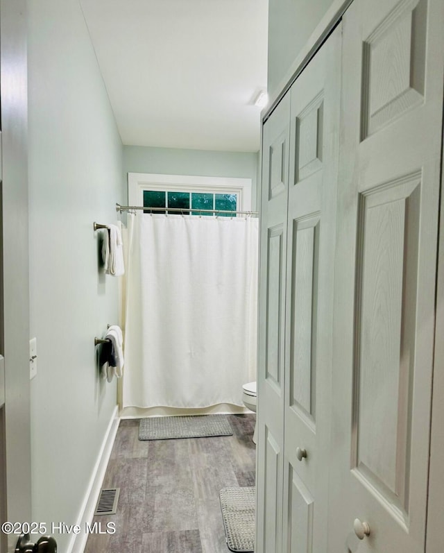 1044 Mill Creek Rd, Minnesott Beach, NC 28510 - full bath with toilet, wood finished floors, baseboards, a shower with shower curtain, and a closet