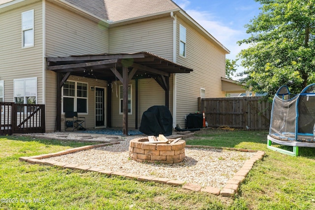 399 Highgrove Dr, Spring Lake, NC 28390 - rear view of property with a trampoline, a fire pit, and a patio area