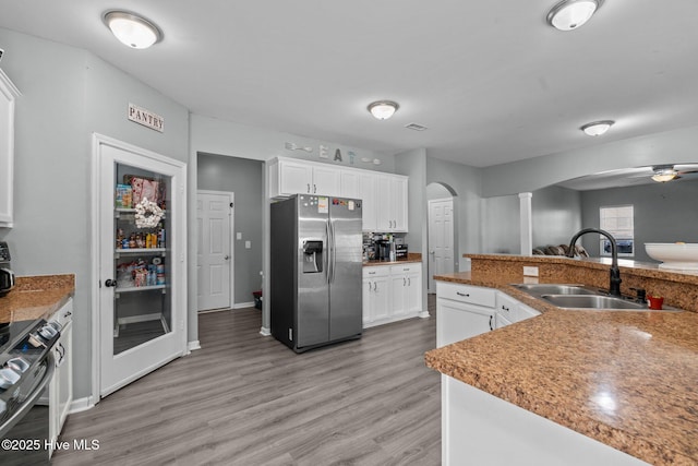 399 Highgrove Dr, Spring Lake, NC 28390 - kitchen featuring stainless steel appliances, arched walkways, a sink, light wood finished floors, and white cabinetry