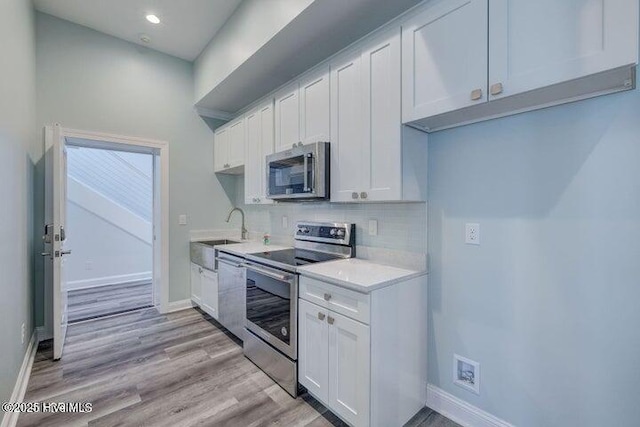 640 Avila Dr, Hampstead, NC 28443 - kitchen featuring appliances with stainless steel finishes, a sink, light countertops, white cabinets, and light wood finished floors