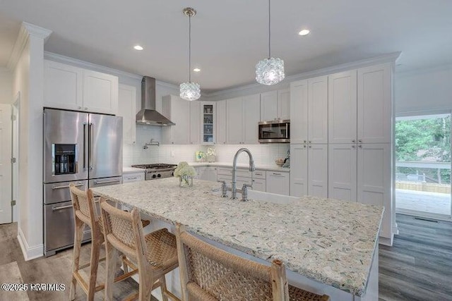 640 Avila Dr, Hampstead, NC 28443 - kitchen featuring wall chimney exhaust hood, stainless steel appliances, wood finished floors, ornamental molding, and white cabinets