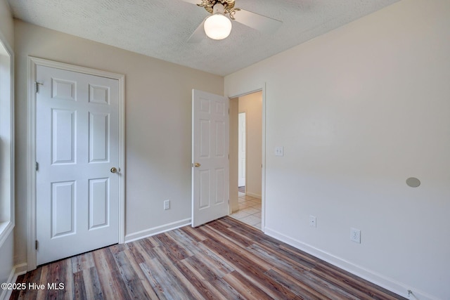 6901 Southern Exposure, Wilmington, NC 28412 - unfurnished bedroom with wood finished floors, baseboards, ceiling fan, and a textured ceiling