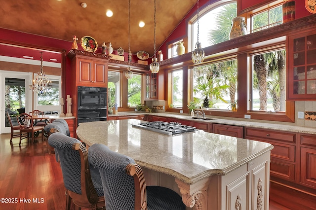 3530 Van Buren St SW, Supply, NC 28462 - kitchen with stainless steel gas cooktop, glass insert cabinets, light stone countertops, a center island, and high vaulted ceiling