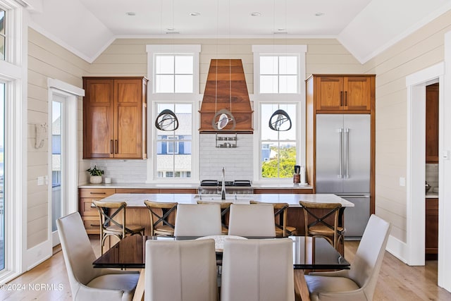 224 W Bald Head Wynd Wynd, Bald Head Island, NC 28461 - kitchen featuring stainless steel built in fridge, vaulted ceiling, brown cabinetry, light wood finished floors, and a center island with sink