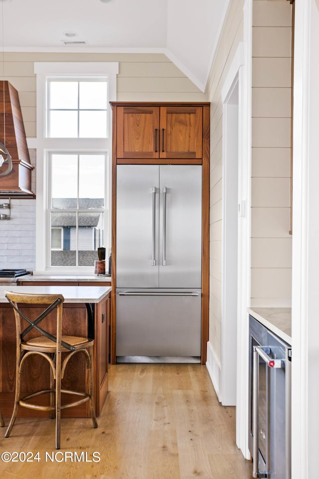 224 W Bald Head Wynd Wynd, Bald Head Island, NC 28461 - kitchen featuring stainless steel built in refrigerator, brown cabinets, light countertops, beverage cooler, and light wood finished floors