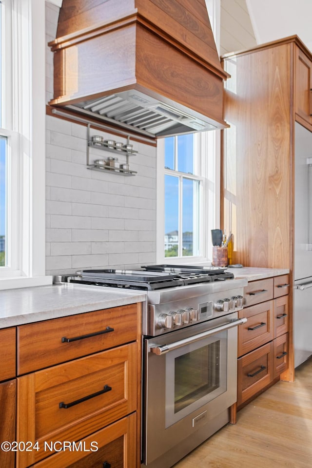 224 W Bald Head Wynd Wynd, Bald Head Island, NC 28461 - kitchen featuring high quality appliances, premium range hood, light wood-style flooring, and brown cabinetry