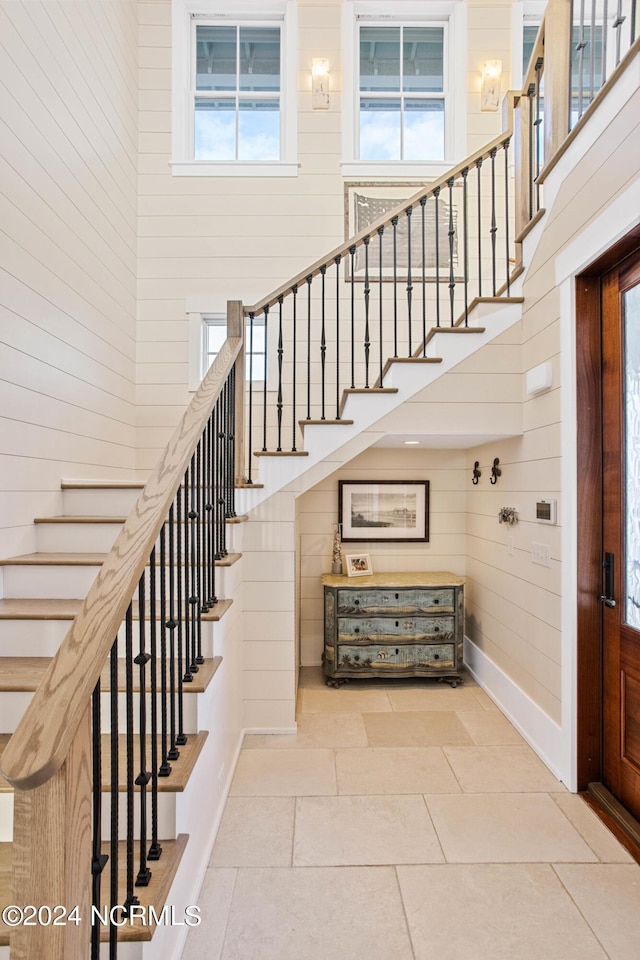 224 W Bald Head Wynd Wynd, Bald Head Island, NC 28461 - stairway featuring a high ceiling, plenty of natural light, wooden walls, baseboards, and tile patterned flooring