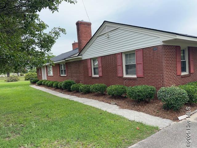 2945 US Highway 17, Williamston, NC 27892 - view of side of home featuring a chimney, brick siding, and a yard