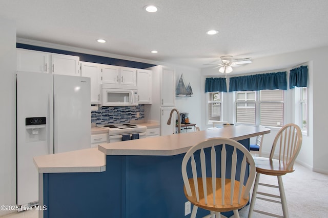 3030 Marsh Winds Cir Unit 605, Southport, NC 28461 - kitchen featuring white appliances, light countertops, white cabinets, a kitchen island with sink, and decorative backsplash