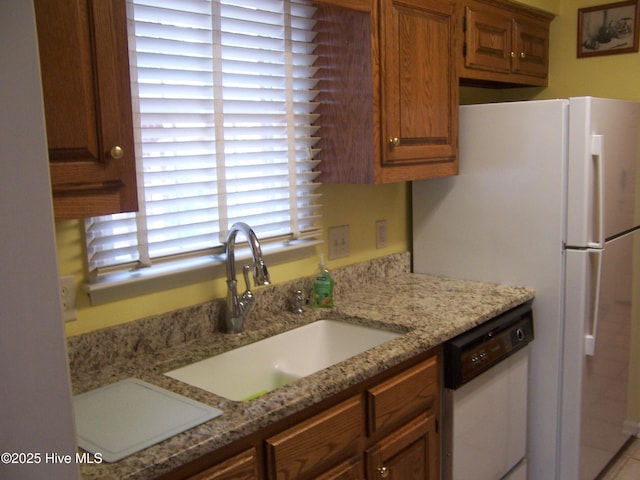 145 Pinehurst Trace Dr, Pinehurst, NC 28374 - kitchen with dishwasher, a sink, freestanding refrigerator, light stone countertops, and brown cabinets