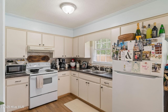 225 Candlewood Dr, Wilmington, NC 28411 - kitchen featuring white appliances, under cabinet range hood, crown molding, dark countertops, and cream cabinetry