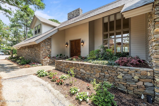 4 Lake Shore Ct, Pinehurst, NC 28374 - property entrance with a chimney, stone siding, and a shingled roof