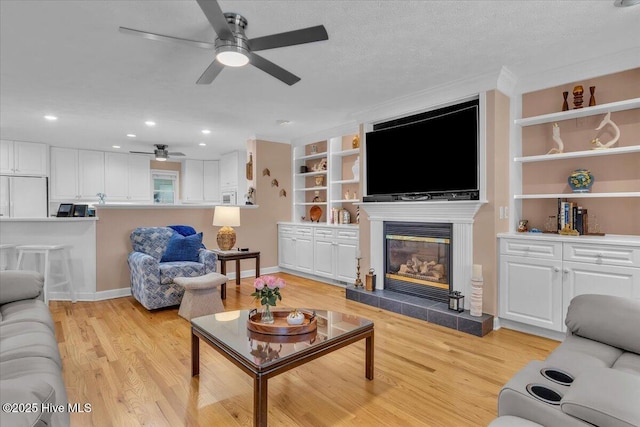 813 Cutter Ct, Kure Beach, NC 28449 - living room featuring a ceiling fan, a tile fireplace, light wood-style flooring, recessed lighting, and built in shelves