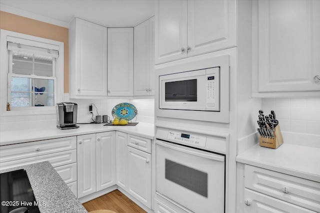 813 Cutter Ct, Kure Beach, NC 28449 - kitchen with white appliances, backsplash, white cabinetry, and light countertops