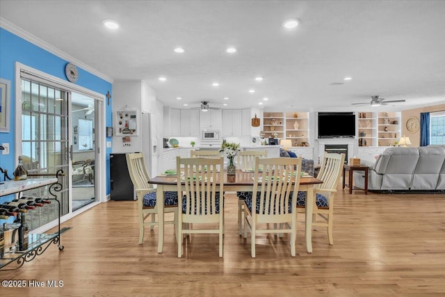 813 Cutter Ct, Kure Beach, NC 28449 - dining room featuring a ceiling fan, crown molding, light wood-style floors, recessed lighting, and a fireplace