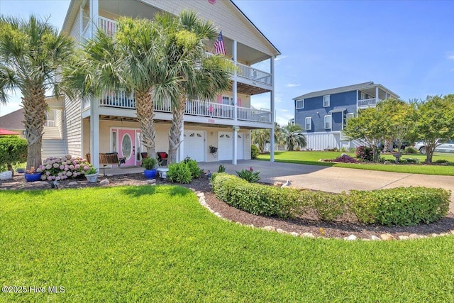 813 Cutter Ct, Kure Beach, NC 28449 - view of front facade with concrete driveway, a garage, a balcony, and a front yard