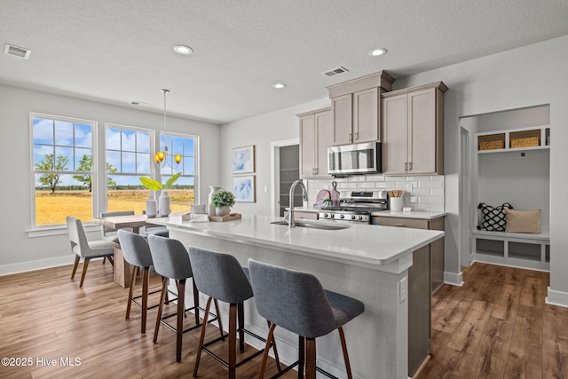 101 Claire Ct, Moyock, NC 27958 - kitchen featuring appliances with stainless steel finishes, a sink, a breakfast bar area, light countertops, and a textured ceiling