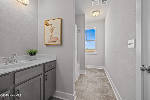 101 Claire Ct, Moyock, NC 27958 - full bath with vanity, a textured wall, baseboards, stone finish flooring, and shower / bath combo with shower curtain