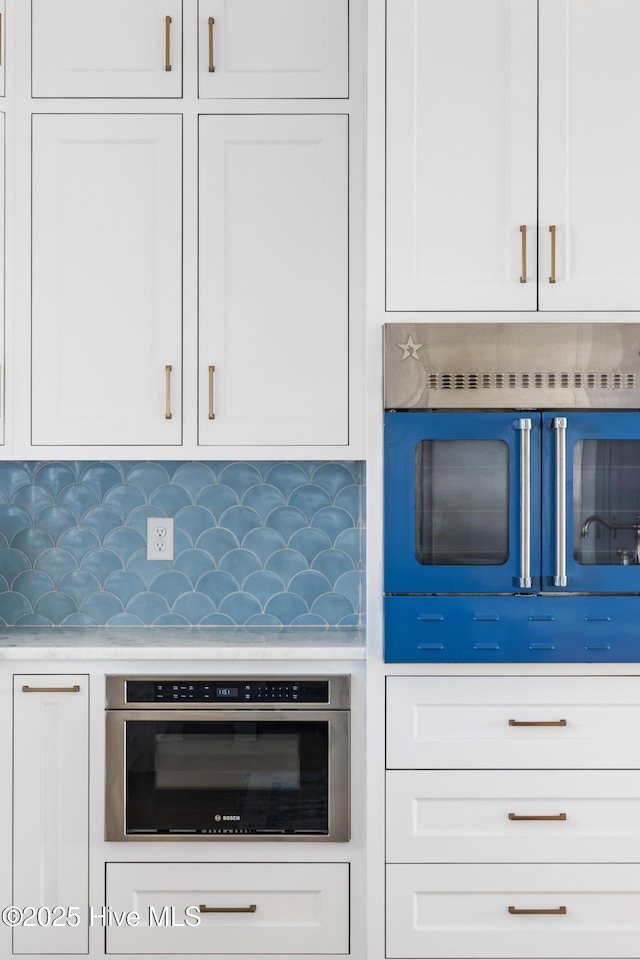 11 Sandspur Trl, Bald Head Island, NC 28461 - kitchen with oven, white cabinets, decorative backsplash, and light countertops
