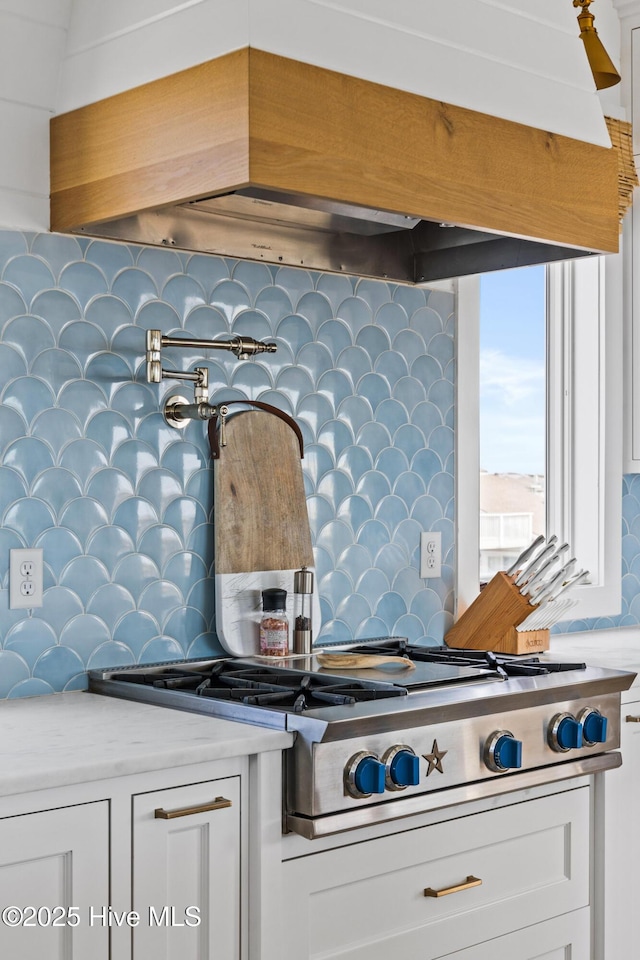 11 Sandspur Trl, Bald Head Island, NC 28461 - kitchen with stainless steel gas cooktop, backsplash, custom exhaust hood, light countertops, and white cabinetry
