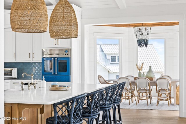 11 Sandspur Trl, Bald Head Island, NC 28461 - kitchen with light wood finished floors, a chandelier, oven, white cabinetry, and beamed ceiling