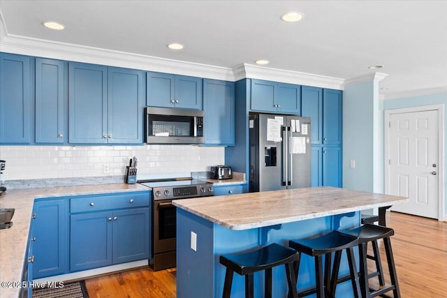1033 Ocean Blvd W, Holden Beach, NC 28462 - kitchen with stainless steel appliances, blue cabinets, a kitchen bar, ornamental molding, and recessed lighting