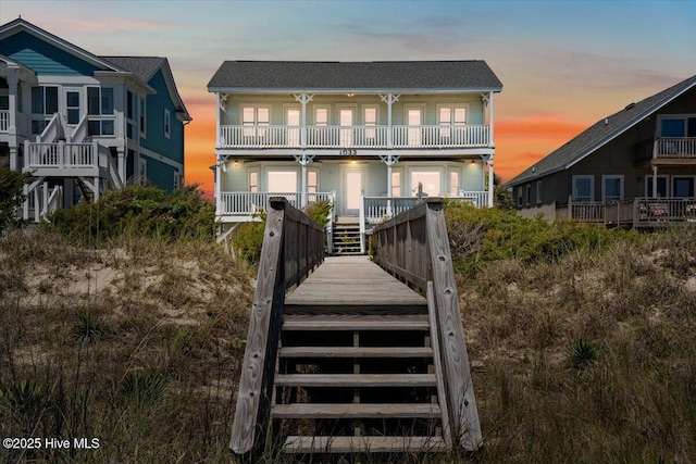 1033 Ocean Blvd W, Holden Beach, NC 28462 - back of property at dusk with a balcony, stairway, and covered porch