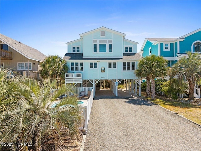 1033 Ocean Blvd W, Holden Beach, NC 28462 - coastal inspired home featuring a carport, gravel driveway, and roof with shingles