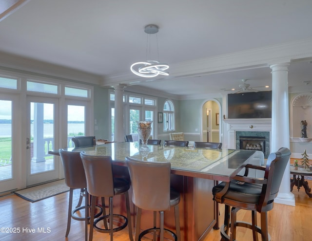 4 Hunter Heath Dr, North Topsail Beach, NC 28460 - kitchen featuring crown molding, plenty of natural light, a fireplace, ornate columns, and light wood-style flooring