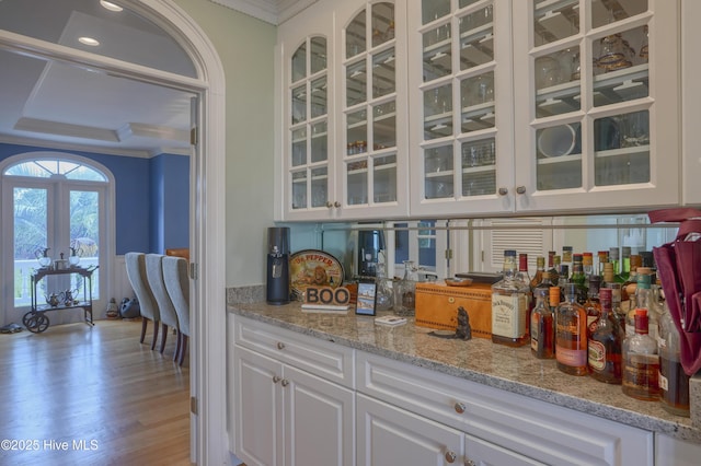 4 Hunter Heath Dr, North Topsail Beach, NC 28460 - kitchen featuring crown molding, white cabinets, glass insert cabinets, light stone countertops, and wood finished floors