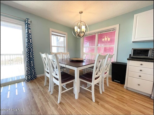 7411 Ocean Dr Unit E & W, Emerald Isle, NC 28594 - dining room with a chandelier, light wood-type flooring, a textured ceiling, and baseboards