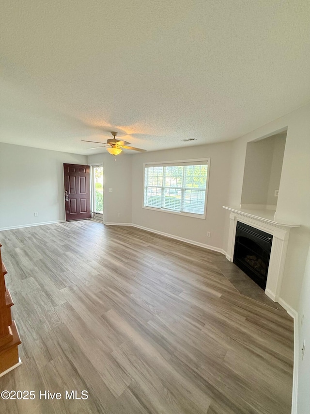 2104 Flagstone Ct Unit A-4, Greenville, NC 27834 - unfurnished living room featuring a fireplace, a textured ceiling, a ceiling fan, wood finished floors, and baseboards