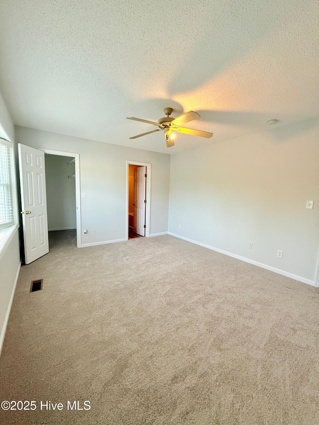 2104 Flagstone Ct Unit A-4, Greenville, NC 27834 - unfurnished bedroom featuring carpet flooring, a textured ceiling, baseboards, a spacious closet, and a ceiling fan