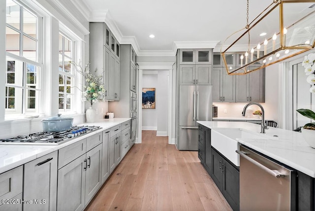 1830 Senova Trce, Wilmington, NC 28405 - kitchen featuring appliances with stainless steel finishes, gray cabinetry, ornamental molding, light stone counters, and light wood finished floors