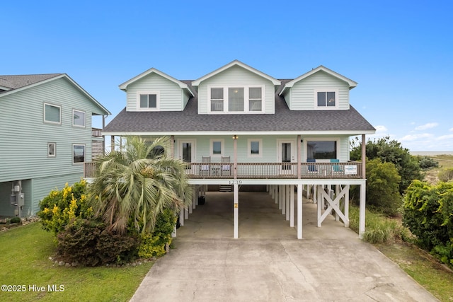 1239 Ocean Blvd W, Holden Beach, NC 28462 - coastal inspired home featuring a carport, driveway, a shingled roof, and a porch