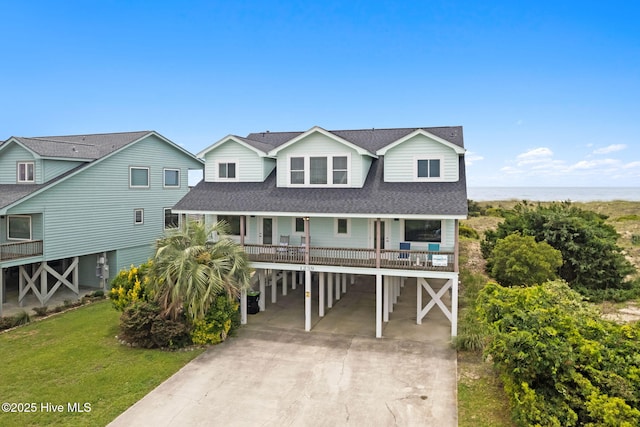 1239 Ocean Blvd W, Holden Beach, NC 28462 - coastal inspired home featuring a carport, a shingled roof, driveway, a porch, and a front lawn