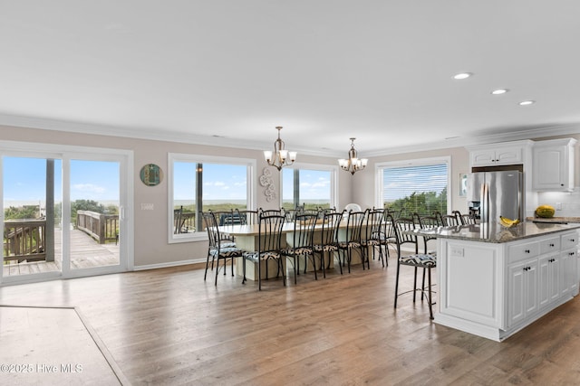 1239 Ocean Blvd W, Holden Beach, NC 28462 - kitchen with stainless steel fridge, a chandelier, healthy amount of natural light, a breakfast bar area, and crown molding