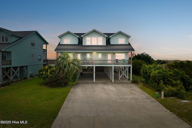 1239 Ocean Blvd W, Holden Beach, NC 28462 - coastal home with a carport, concrete driveway, a yard, a porch, and a shingled roof