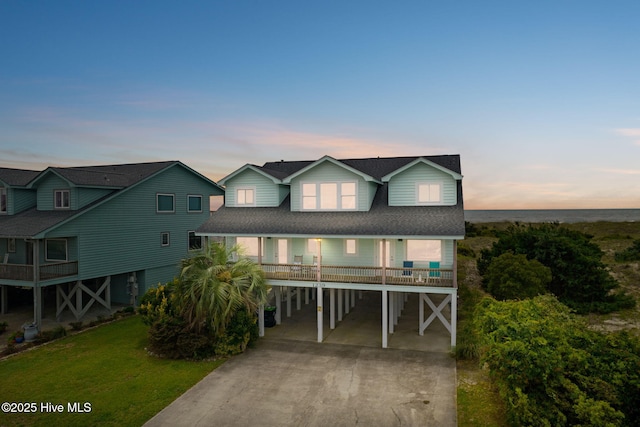1239 Ocean Blvd W, Holden Beach, NC 28462 - coastal inspired home with a carport, driveway, a shingled roof, and a lawn