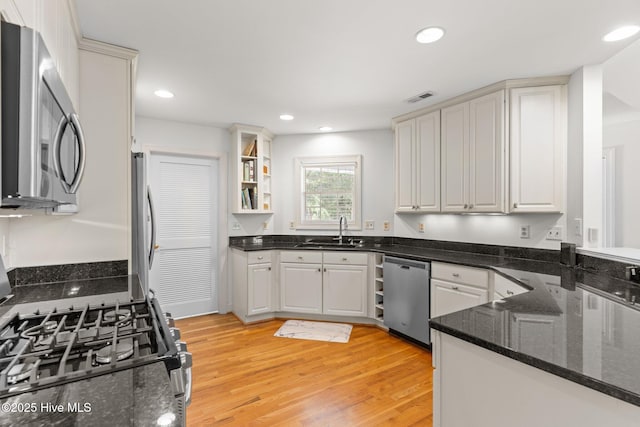 5752 Gardenia Ln, Wilmington, NC 28409 - kitchen featuring stainless steel appliances, a sink, light wood-type flooring, dark stone counters, and recessed lighting
