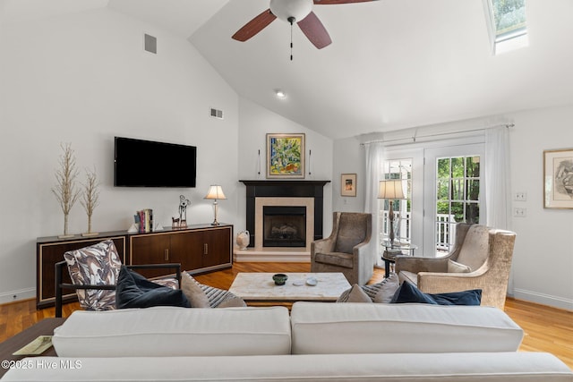 5752 Gardenia Ln, Wilmington, NC 28409 - living room with a fireplace with raised hearth, ceiling fan, baseboards, wood finished floors, and high vaulted ceiling