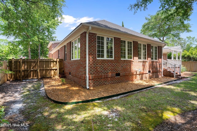 5752 Gardenia Ln, Wilmington, NC 28409 - view of home's exterior featuring crawl space, brick siding, a pergola, and roof with shingles