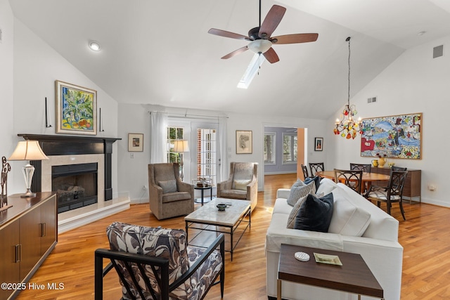 5752 Gardenia Ln, Wilmington, NC 28409 - living room featuring plenty of natural light, a ceiling fan, a tiled fireplace, light wood finished floors, and high vaulted ceiling