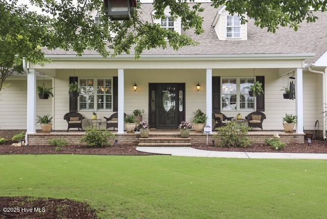 1 Burton Pl, Jacksonville, NC 28540 - doorway to property featuring covered porch, a lawn, and a shingled roof