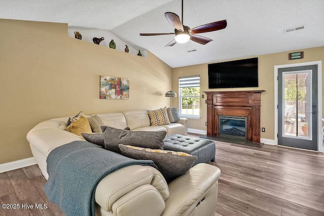 648 Pine Branches Cir SE, Leland, NC 28451 - living room with a ceiling fan, lofted ceiling, wood finished floors, a glass covered fireplace, and a textured ceiling