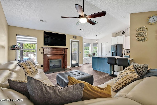 648 Pine Branches Cir SE, Leland, NC 28451 - living area with a textured ceiling, plenty of natural light, ceiling fan, wood finished floors, and a glass covered fireplace