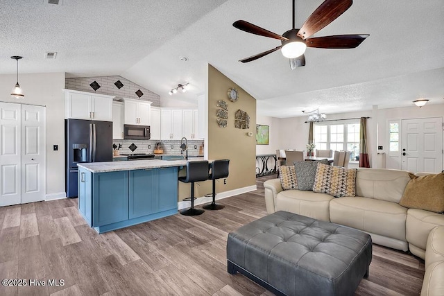 648 Pine Branches Cir SE, Leland, NC 28451 - living area with lofted ceiling, a ceiling fan, a textured ceiling, wood finished floors, and a chandelier