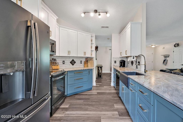 648 Pine Branches Cir SE, Leland, NC 28451 - kitchen featuring appliances with stainless steel finishes, blue cabinetry, white cabinetry, open shelves, and wood finished floors