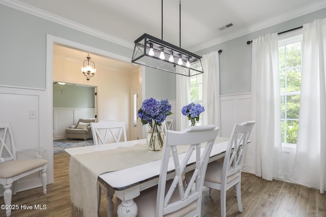 637 White Oak Xing, Swansboro, NC 28584 - dining area featuring a decorative wall, crown molding, a chandelier, wood finished floors, and wainscoting