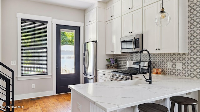 359 N Leak St, Southern Pines, NC 28387 - kitchen with appliances with stainless steel finishes, decorative backsplash, baseboards, light wood-style floors, and light stone countertops